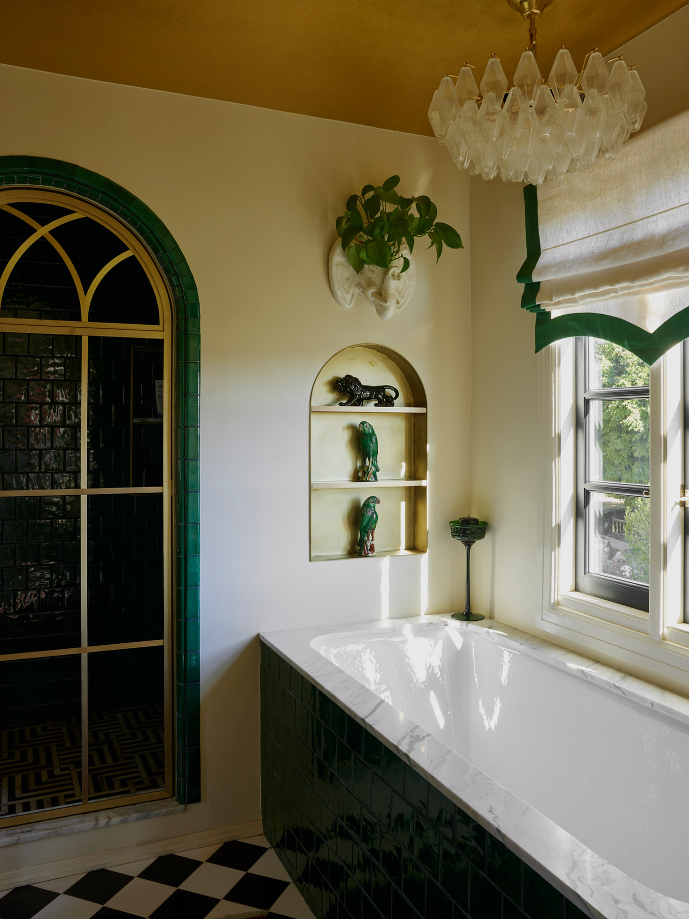 Arched window and freestanding tub in a Studio Nauleau bathroom with green trim