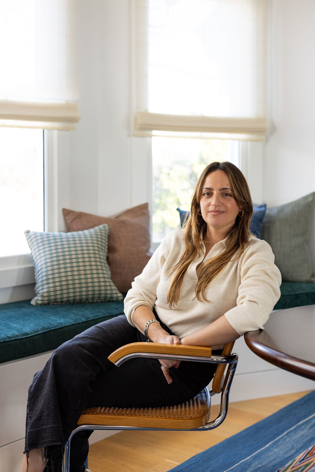 Daphne Nauleau, principal interior designer of Studio Nauleau, seated by a window in a styled San Francisco interior